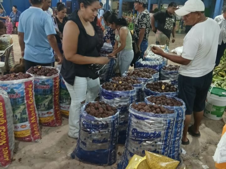 Sacos de aguaje abiertos en el pasillo del mercado, con compradores escogiendo