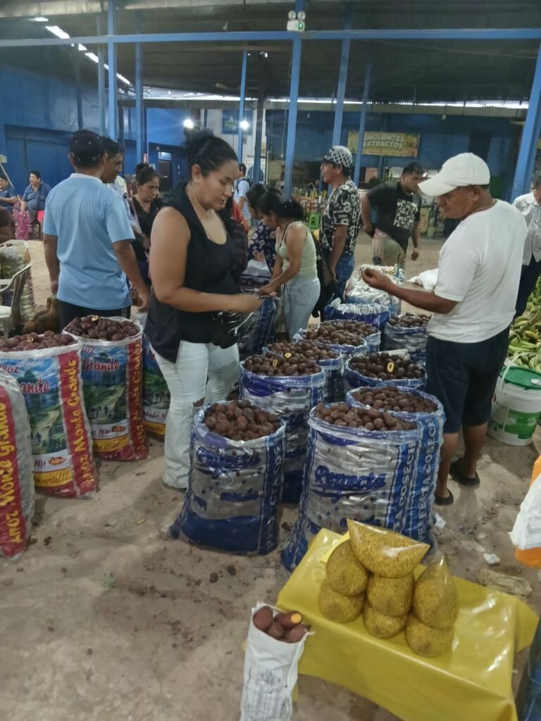 Sacos de aguaje abiertos en el pasillo del mercado, con compradores escogiendo